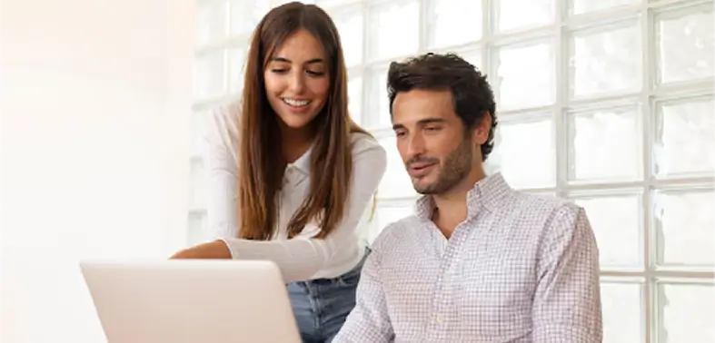 Pareja trabajando junta en una computadora portátil en un ambiente de una oficina, mostrando colaboración y concentración